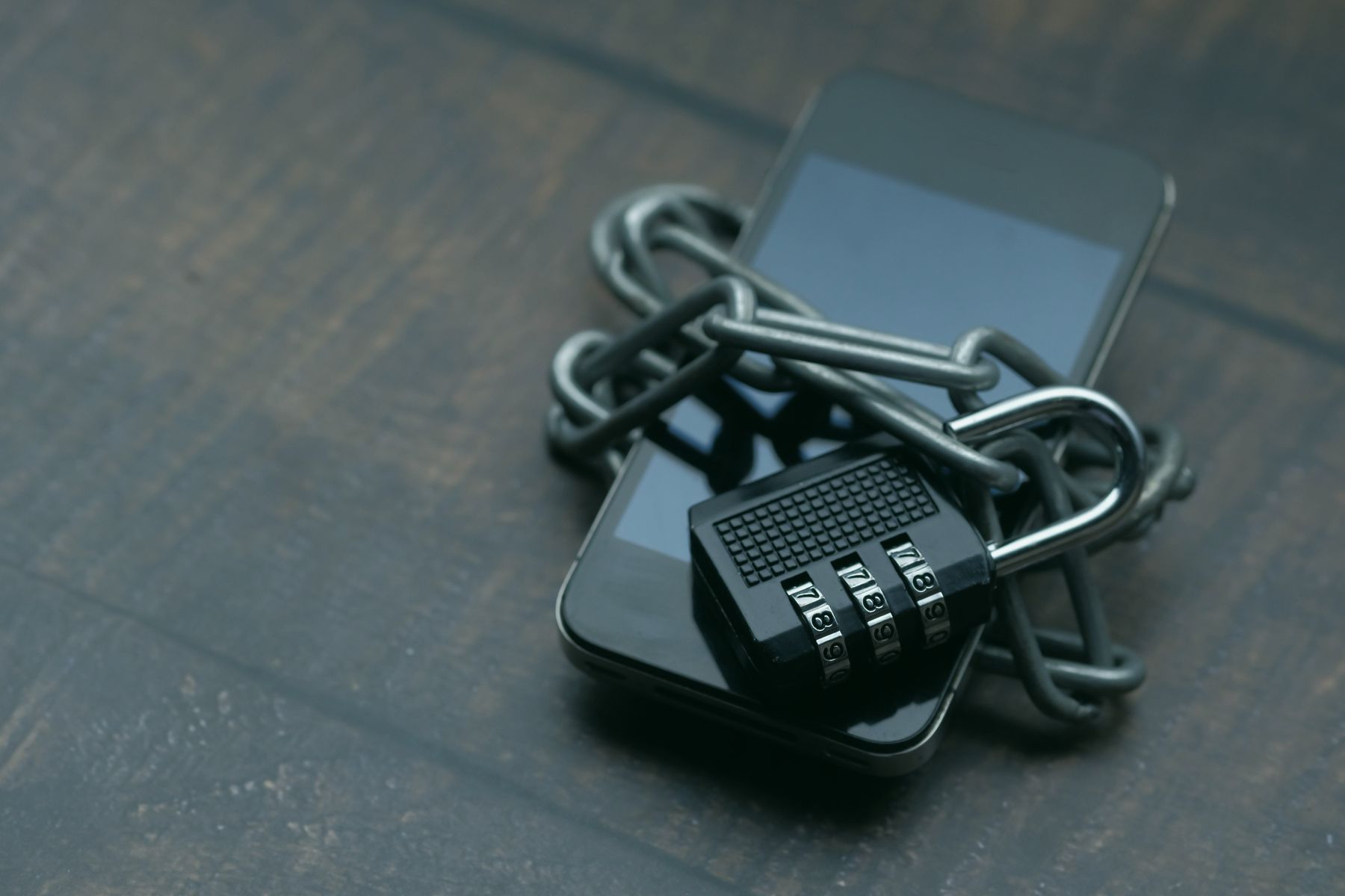 A phone wrapped in a chain and locked with a combination padlock.